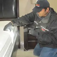 Bed bug inspection technician checking a mattress and bed frame for signs of infestation in Erie, PA