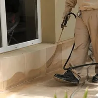General pest control technician spraying exterior perimeter around a home in Erie, PA