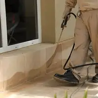 General pest control technician spraying exterior perimeter around a home in Erie, PA